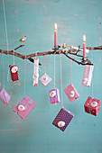Selbstgebastelter Adventskalender aus Zweig mit Kerzen, Dekovögeln und Päckchen