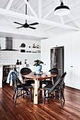 Round table and black chairs in dining area in front of fridge and white kitchen counter