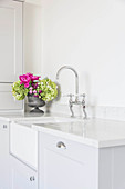 Flower arrangement next to sink in bright country-house kitchen