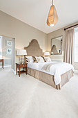 Bett mit geschwungenem Betthaupt im eleganten Schlafzimmer in Grau