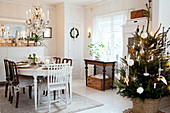 Festively decorated dining table and decorated Christmas tree in Scandinavian dining room