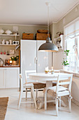 Round dining table and chairs in white, rustic kitchen