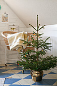 Small Christmas tree and crib in attic room with blue-and-white chequered wooden floor