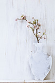 A homemade painted plywood vase, with a cherry and apple blossom branch