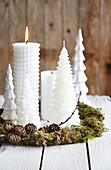 White Christmas candles in handmade wreath of moss and larch twigs