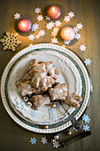 Plate of gingerbread biscuits surrounded by Christmas decorations