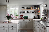 Panelled cabinets and shelves in pale country-house kitchen