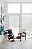 Vintage Sessel und Beistelltische mit Bücherstapel vor Terrassentür, Gemälde an weißer Holzwand