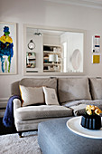 Hellgraues Sofa vorm Wandspiegel im klassischen Wohnzimmer