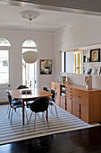 Designer chairs around dining table on striped rug in period building