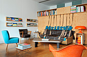 Sofa mit dünner Lederdecke an Sperrholzplatte und verschiedene Retro Stühle im Loft
