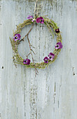 Wreath of heather decorated with purple violas and twig