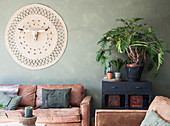 Brown leather sofas and wall hanging with animal skull in living room with green wall