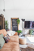 Brown leather sofa, chalkboard, standard lamp and vintage TV stand in living room