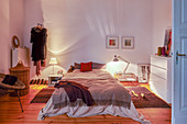 Two lit bedside lamps in bedroom with wooden floor