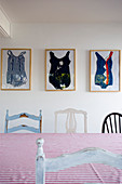 Framed bathing suits behind various chairs in dining room
