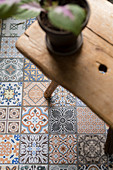 House plant on wooden stool on floor tiles with Oriental patterns