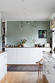 White cupboards in kitchen with pale grey wall