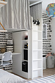 Loft bed above desk and shelving in child's bedroom with black-and-white wall