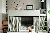 Loft bed with curtains screening cosy den below in child's bedroom