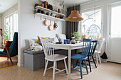 Wooden dining table with white and blue chairs and dog sitting on bench