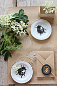Still-life arrangement with elderflowers, plates with ladybird motifs and paper crafts