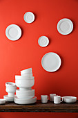 White crockery on table and white plates on red wall