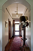 Hats on coat stand in hallway with front door at far end