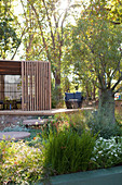 Holzpavillon auf halbhoher Natursteinmauer im Garten