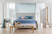 White double bed with headboard and pastel-blue bed linen in open-plan bedroom with partition wall