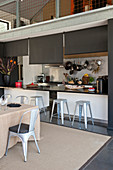 Counter and barstools in open-plan kitchen below gallery