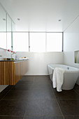 Free-standing bathtub and wooden floating washstand in bathroom