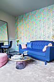 Blue sofa against gold-patterned wallpaper in elegant living room