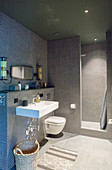 Round, black mosaic tiles in modern bathroom with open-plan shower area