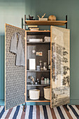 Bathroom utensils in old, refurbished wardrobe covered with vintage-style wallpaper
