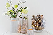 Silk flowers in milk churn, branches of blackthorn and olive, candle lanterns and glass vase filled with pine cones and fairy lights