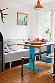 Old wooden table with blue-painted base and bench in kitchen-dining room