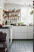 White kitchen counter with concrete worksurfaces and Moroccan tiles on floor
