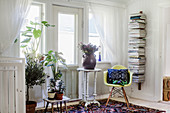 Shell chair, bookshelves and plant stands below window