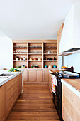 Kitchen area with light wooden furniture and generous ceiling-high built-in wall unit