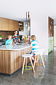 Family around middle block with marble top in open kitchen