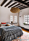 Double bed with bedspread, Moroccan lamp in the bedroom with dark beams