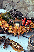 Candle lantern surrounded by leaves, bark, pine cones and rose hips