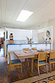 Chairs around dining table with cherub ornaments in front of kitchen counter and fitted kitchen in open-plan interior
