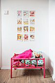 Scandinavian postcards on wall above pink dolls' bed