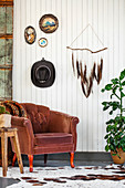 Brauner Sessel, darüber DIY-Dekoration an weiß gestrichener Holzwand