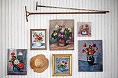 Blumenbilder, Vintage Rechen und Hut an weiß gestrichener Holzwand
