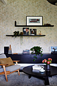 Retro-Sessel und schwarze Möbel vor Blumentapete im Wohnzimmer