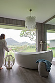 Free-standing oval bathtub in modern bathroom with panoramic windows