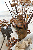 Metal animal figurines amongst autumnal twigs and acorns